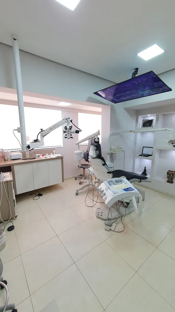 Sala com microscópio operatório montado sobre a cadeira odontológica