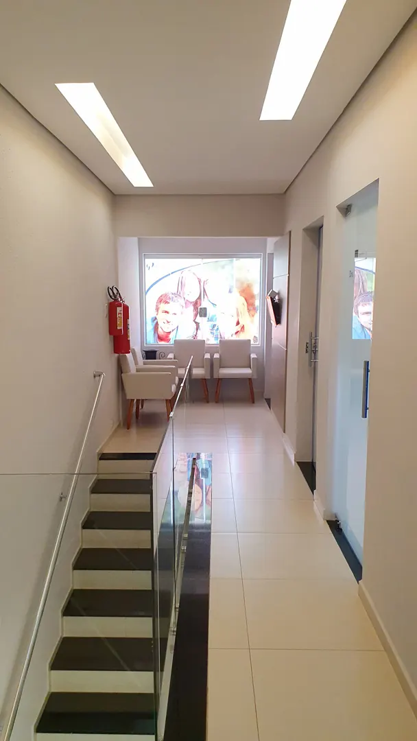 Escada interna de acesso ao segundo piso, com corrimão de vidro