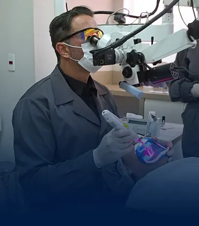 Dr. Rodrigo Mariani trabalhando ao microscópio operatório durante um atendimento